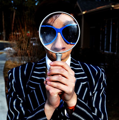 man met zonnebril kijkt door vergrootglas